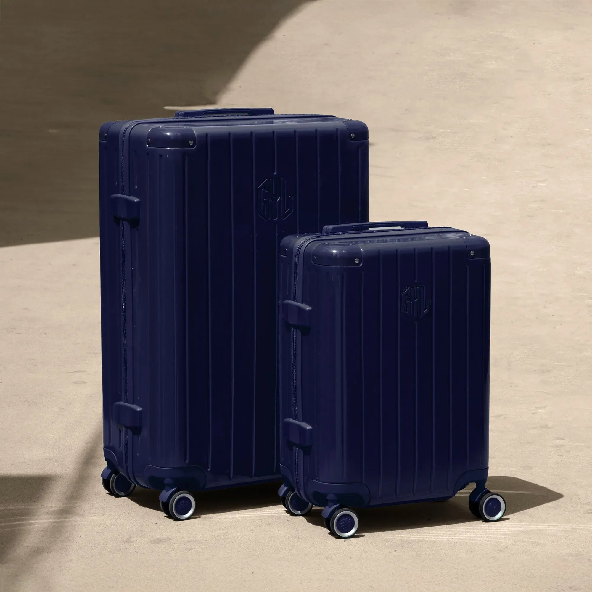 Set of two GYL Intemporelle navy hard-shell suitcases, cabin and hold sizes, placed on a concrete floor. #couleur_marine