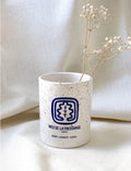 Ines De La Fressange – Tazza In Ceramica - Paris Annecy Doha, vaso in ceramica bianco maculato con motivo blu, con all'interno fiori secchi