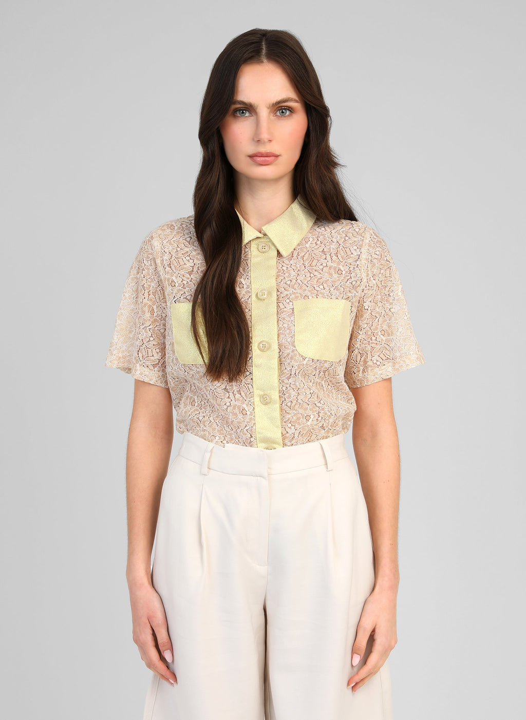 An'ge – Camicia Atimio Gold, modella che indossa una camicia in pizzo beige e pantaloni bianchi