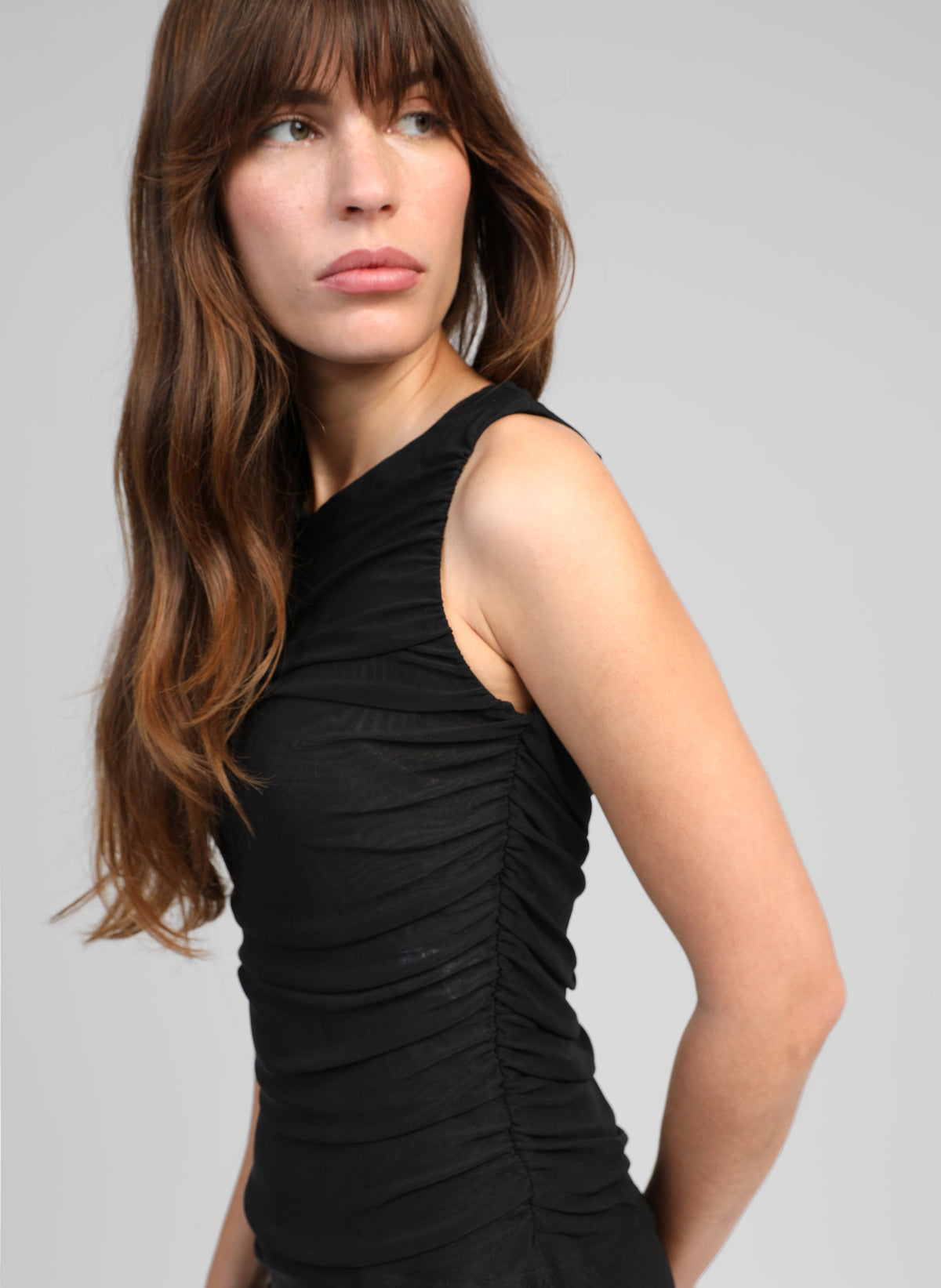 An'ge – Canotta Azilou Noir, modella con top nero arricciato, vista di profilo, capelli castani