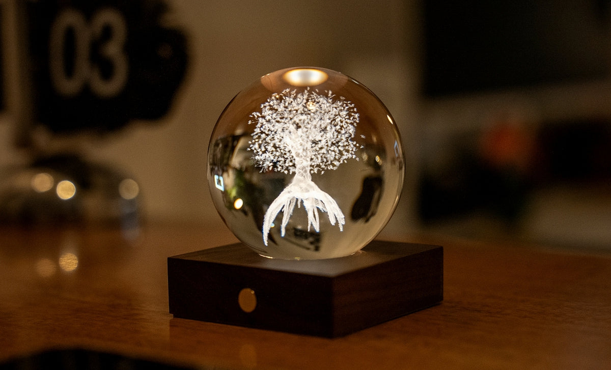 Gingko Design – Luce Amber Crystal - Albero della Vita, una sfera di vetro con un albero luminoso su una base di legno