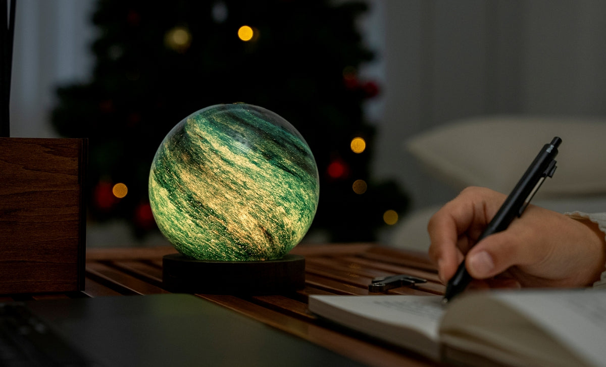 Gingko Design – Astraglass Leuchte - Stellar Ocean - 2 Größen, kugelförmige grün-gelbe Nachttischlampe auf einem Tisch