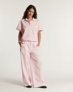 Light pink poplin pants, wide and fluid cut, light cotton material suitable for summer, offering comfort and an elegant silhouette.