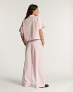 Jean pour femme en popeline légère rose pâle, coupe large et fluide, tissu coton doux parfait pour l'été, offrant un confort et une élégance décontractée.