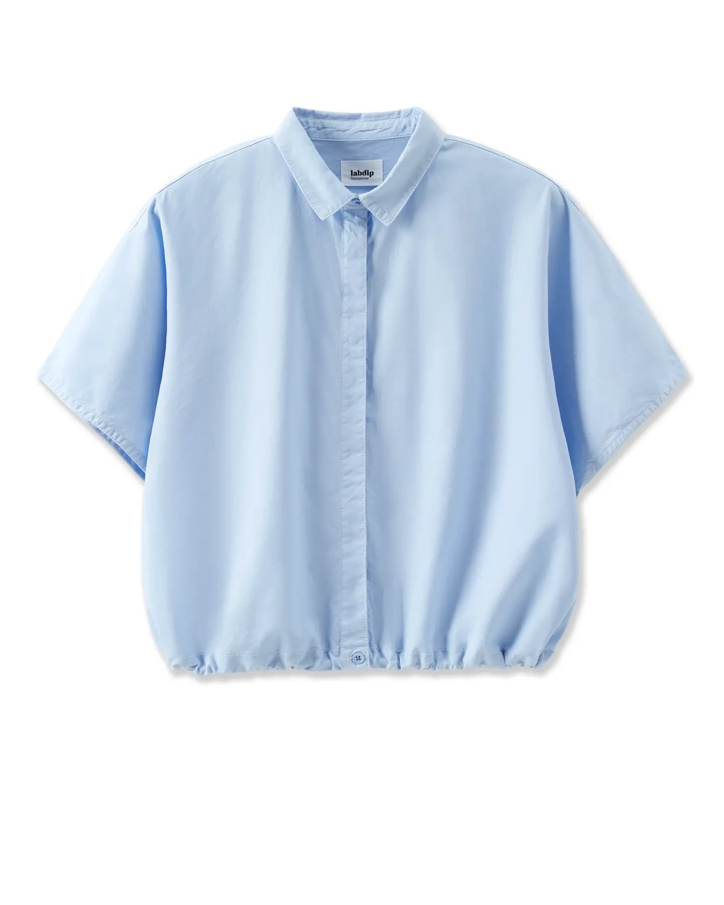 Camisa de popelín azul claro, corte holgado y corto con manga ancha y cuello clásico, tejido suave y fluido ideal para el verano.