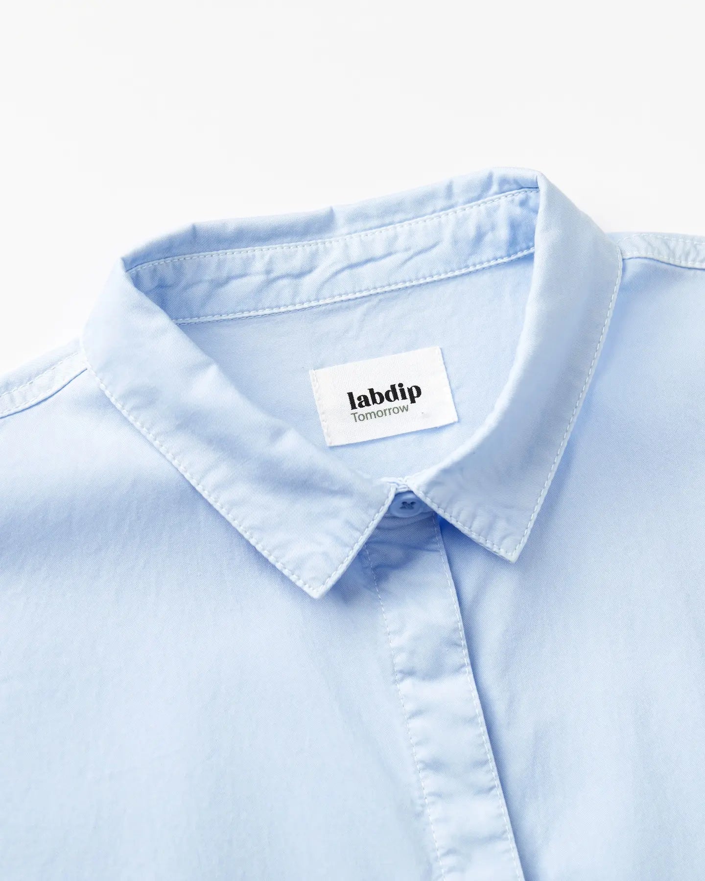 Cuello camisero azul claro en popelina ligera, tejido suave y transpirable ideal para un estilo veraniego elegante y confortable.