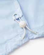 Detalle de bajo en popelina celeste claro con cordón ajustable, tejido suave y fluido para un corte femenino adaptable y cómodo.