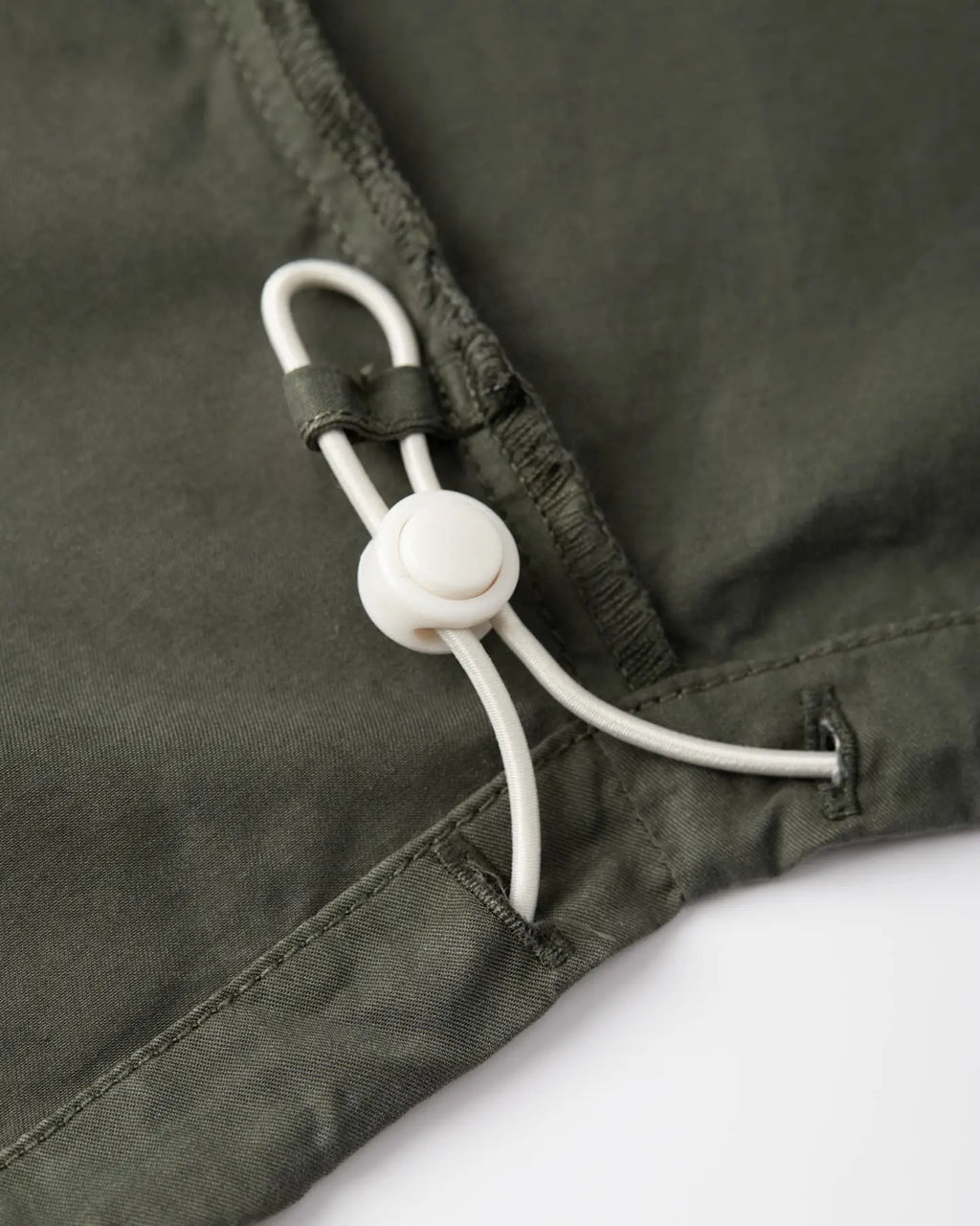 Zoom sur un pantalon en popeline kaki, tissu léger en coton, coupe droite avec cordon de serrage ajustable pour un confort personnalisé.