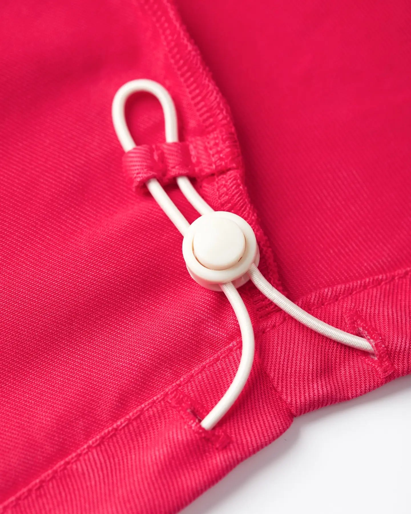 Detail of the bright red tencel fabric, smooth and light texture with adjustable elastic cord for a personalized fit of the women's jeans.