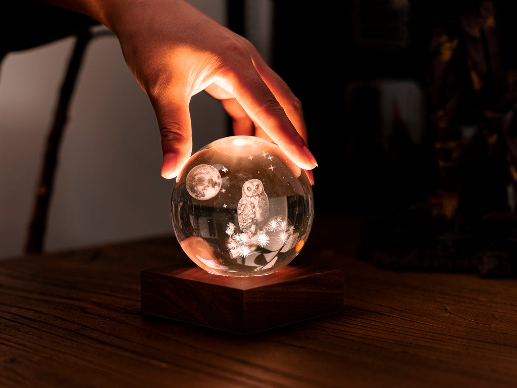 Gingko Design – Amber Crystal Light - Uil en Maan, hand rustend op een oplichtende kristallen bol met een uil