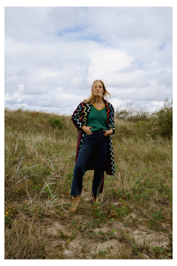 Michonet – Cappotto Lungo, modella bionda con cappotto lungo colorato, maglione verde e jeans blu