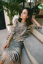 Michonet – Kleid Hoja Beig, sitzendes Model, Zebrakleid in Beige und Schwarz, Seitenansicht