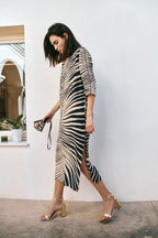 Michonet – Kleid Hoja Beig, Model im Profil im langen Zebrakleid und goldenen Sandalen