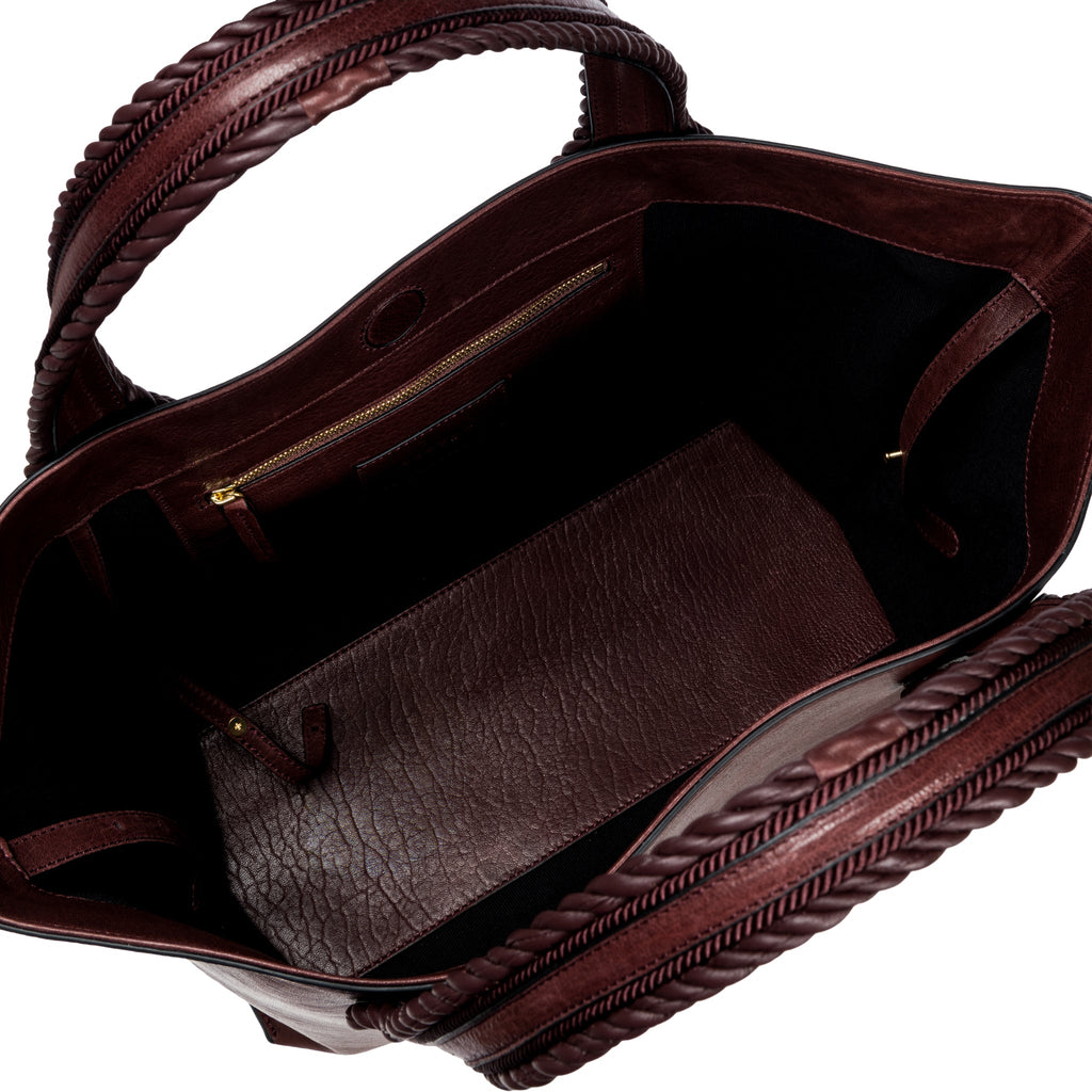 Close-up of a burgundy leather in a shade of dark cherry bag with a same tone interior. It has an inner pocket with zip and keys strap.