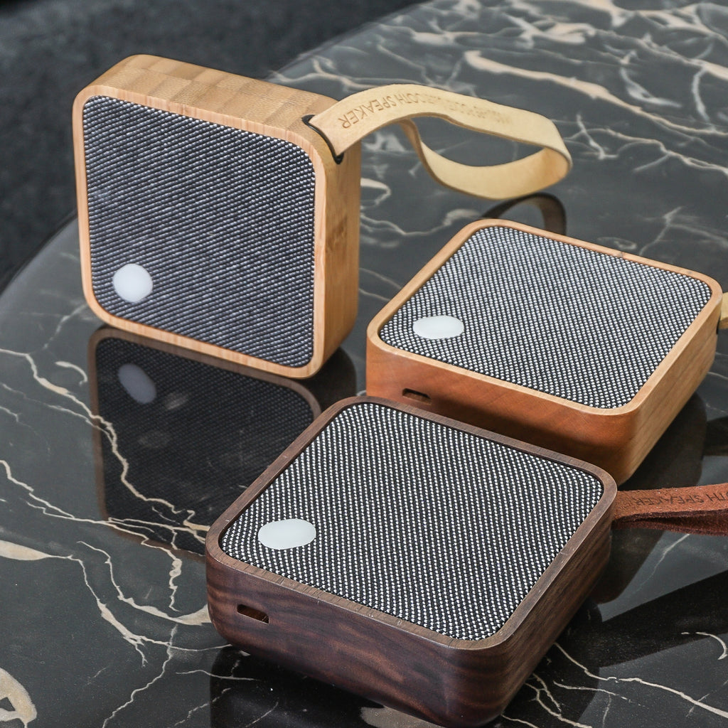 Gingko Design – Bluetooth-luidspreker MI Square - Natuurlijk kersenhout, drie draagbare luidsprekers van hout en stof, op een marmeren tafel