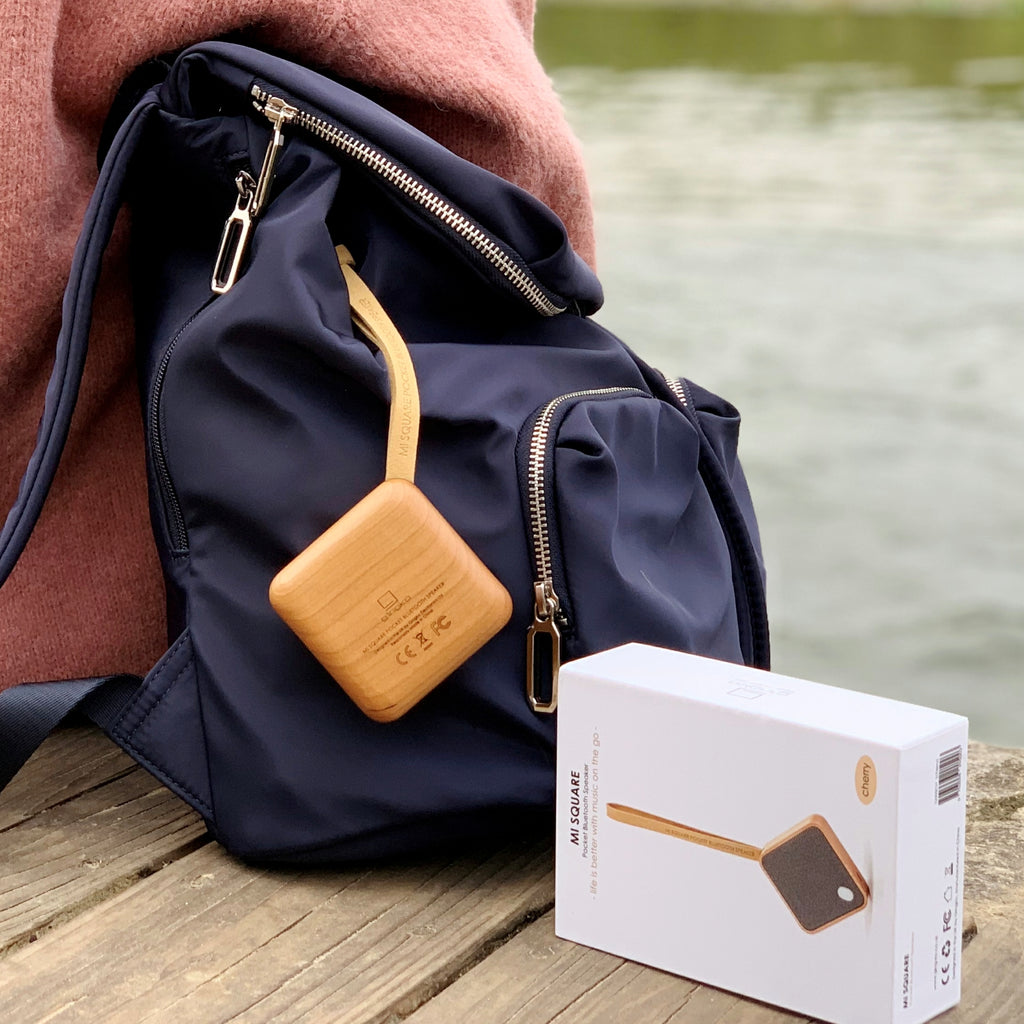 Gingko Design – Bluetooth-luidspreker MI Square - Natuurlijk kersenhout, draagbare houten oplader bevestigd aan een blauwe rugzak