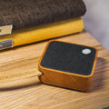 Gingko Design – Bluetooth-luidspreker MI Square - Natuurlijk kersenhout, bluetooth-luidspreker van licht hout en zwarte stof, op een houten tafel