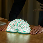 Gingko Design – Lampe Smart Accordion - Velours Bleu Géometrique, une lampe en forme d'accordéon ouverte sur une table en bois