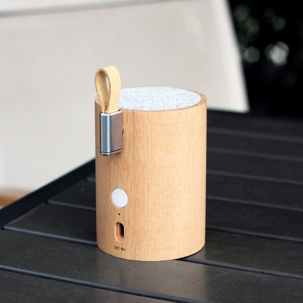Gingko Design – Altavoz Bluetooth Drum Light - Haya Natural, altavoz cilíndrico de madera clara colocado sobre una mesa negra