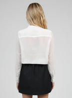 An'ge – Falda Corta Gilma Negro, modelo de espaldas con camisa blanca transparente y falda negra