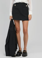An'ge – Falda Corta Gilma Negro, modelo con falda negra con bolsillos y botones dorados