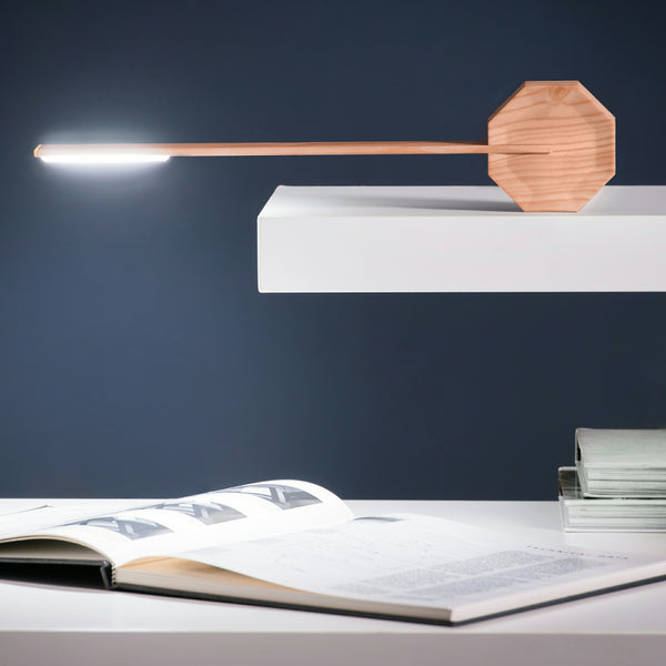 Gingko Design – Lámpara de Escritorio Octagon One - Arce, lámpara de escritorio de madera clara, encendida, sobre una estantería blanca