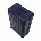 Angled view of the GYL Intemporelle navy hard-shell suitcase with reinforced corners and glossy ribbed shell. #couleur_marine
