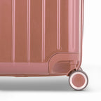 Detail of the wheel and GYL logo on the bottom of the rose gold trunk suitcase in glossy polycarbonate. #couleur_rose gold