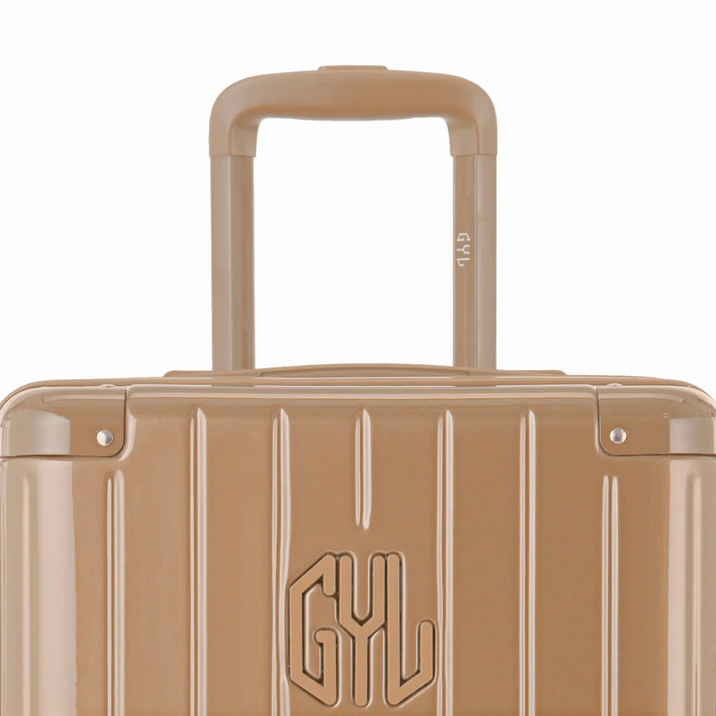 Close-up on the trolley handle and GYL logo of the champagne trunk suitcase. #couleur_champagne