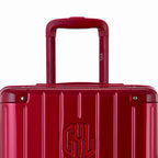 Close-up on the trolley handle and GYL logo of the dark red trunk suitcase. #couleur_red foncé