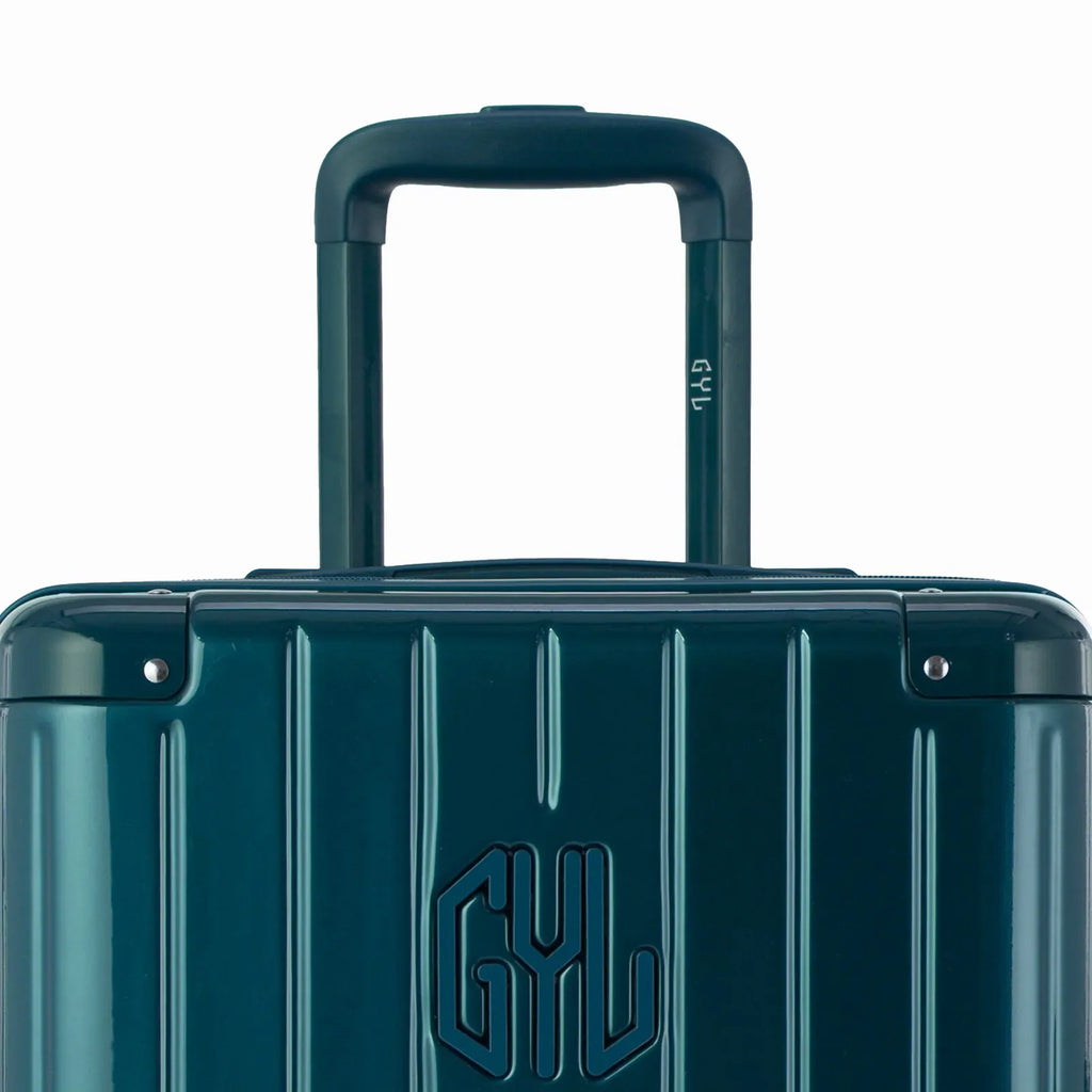 Close-up of the trolley handle and GYL logo on the fir green trunk suitcase. #couleur_sapin