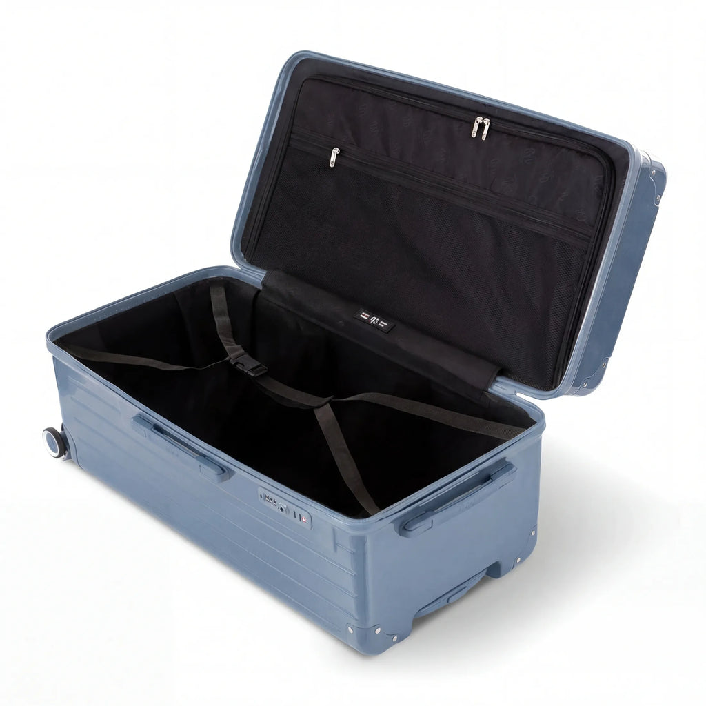 Interior of the open GYL XL dark blue-grey trunk suitcase, with crossed straps. #couleur_bleu grisée