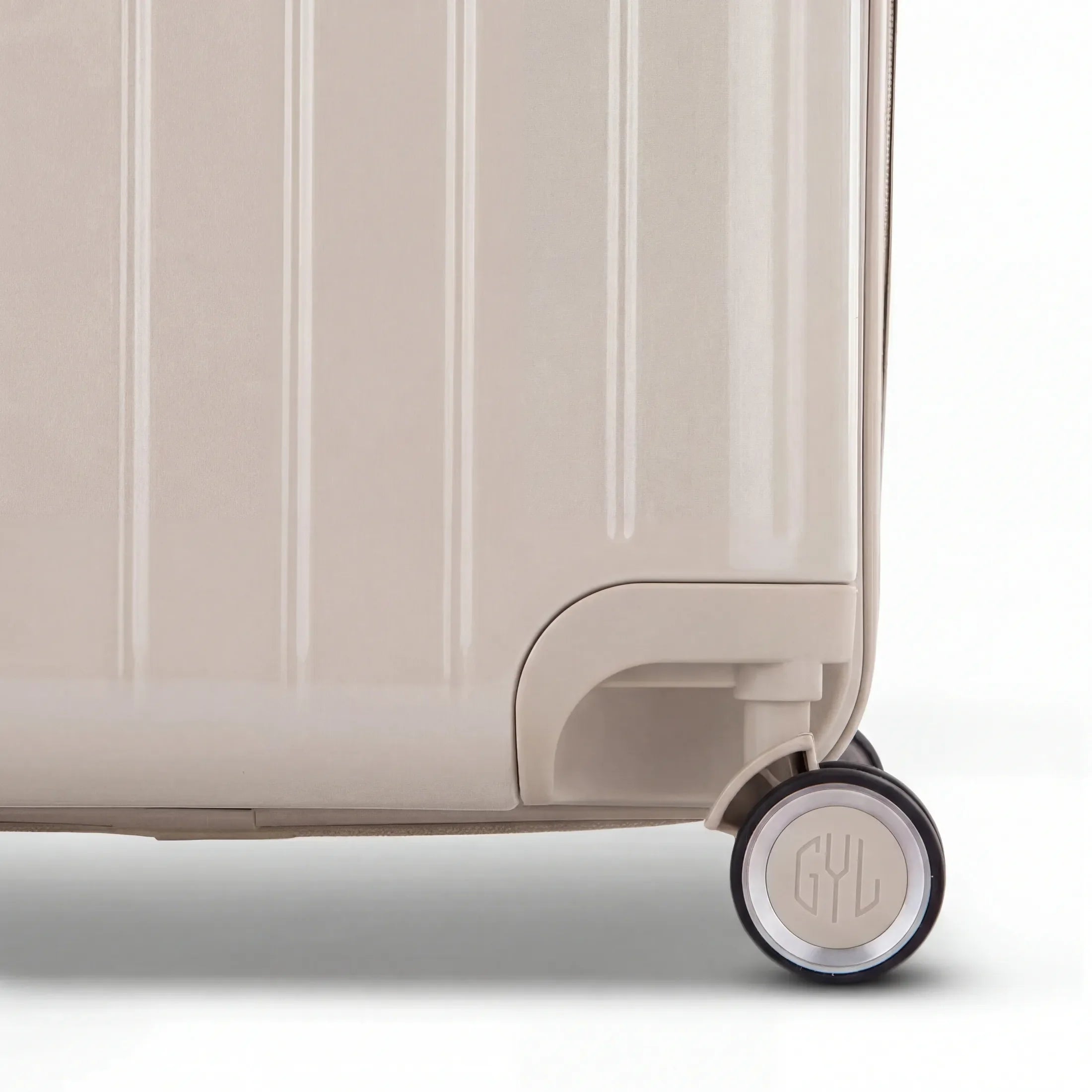 Detail of the wheel and GYL logo on the bottom of the nude trunk suitcase in glossy polycarbonate. #couleur_nude