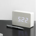Gingko Design – Despertador Brick Click - Blanco / LED Blanco, despertador digital de madera clara sobre una mesa negra