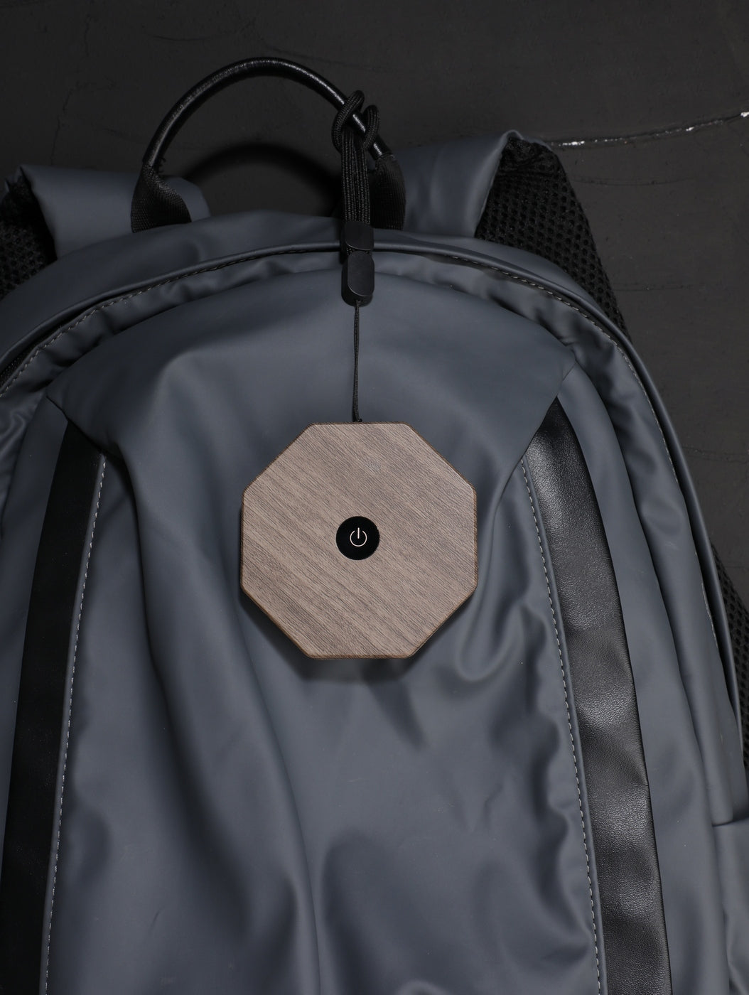 Gingko Design – Lumière Twist Hexagon - Noyer Flotté - Mini, sac à dos gris avec un accessoire en bois accroché sur le devant