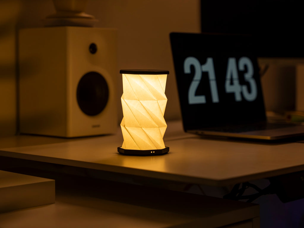 Gingko Design – Luz Twist Hexagon - Negro Pizarra - Mini, lámpara de mesa plegable encendida sobre un escritorio con un ordenador portátil