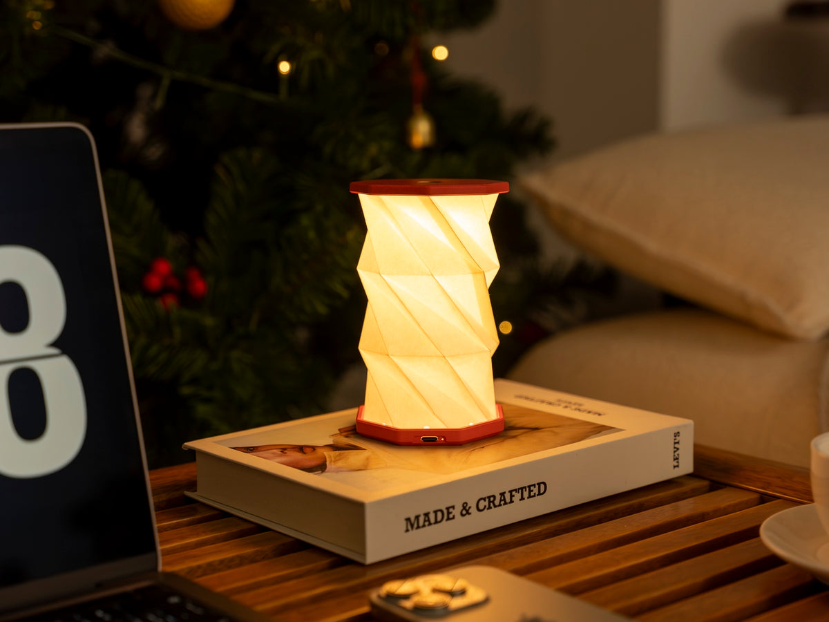 Gingko Design – Lumière Twist Hexagon - Rouge Corail - Mini, lampe de table lumineuse sur un livre dans un salon