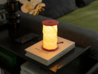 Gingko Design – Lumière Twist Hexagon - Rouge Corail - Mini, lampe de table rouge et blanche allumée sur un livre blanc