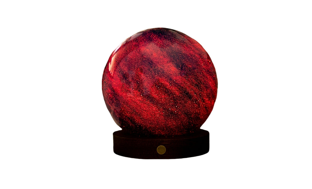Gingko Design – Astraglass-lys - Galaxy Breeze - 2 Størrelser, kugleformet rød og sort bordlampe på en mørk base