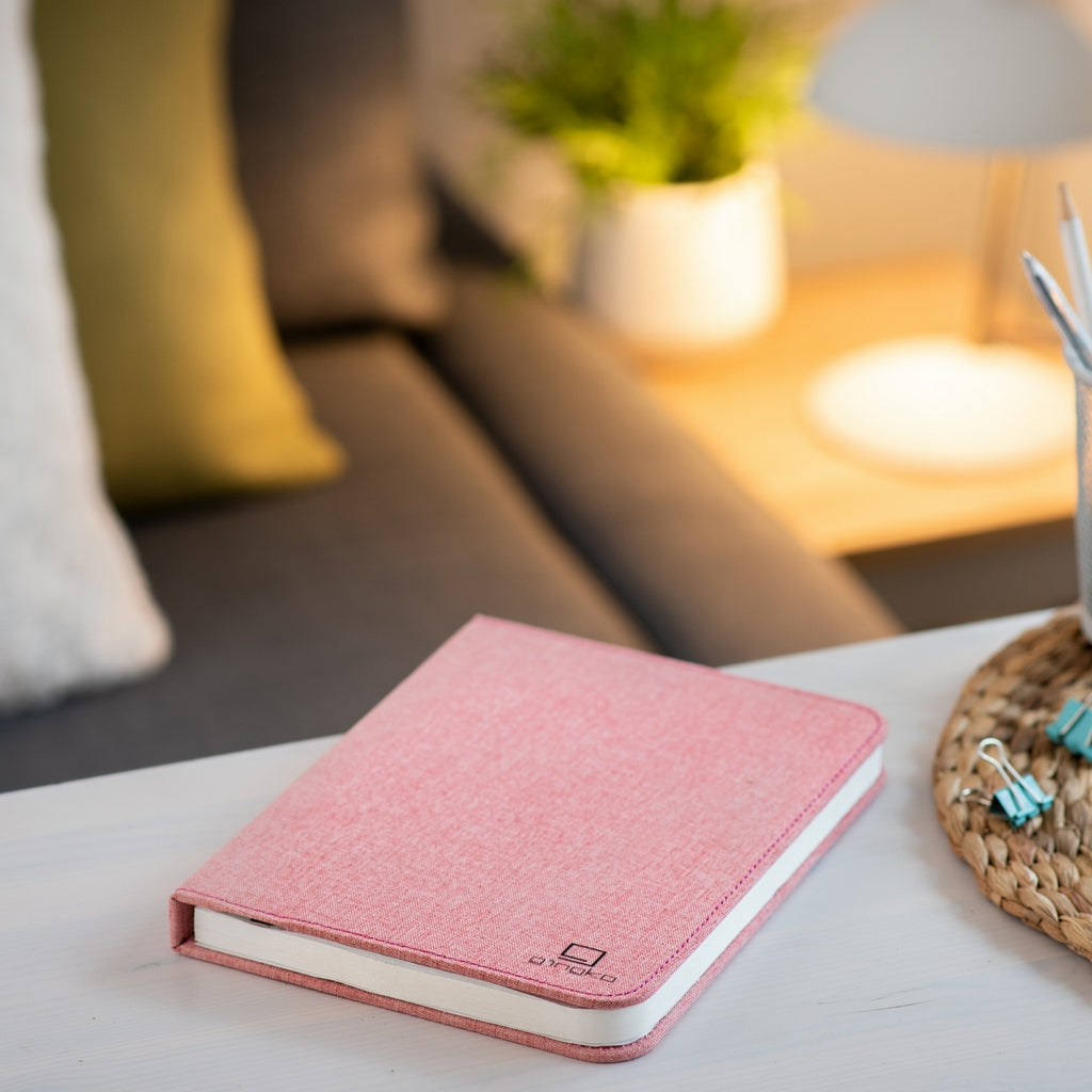 Gingko Design – Lampe Smart Book LED - Lin Rose Poudré - 2 Tailles, carnet rose en tissu posé sur une table basse dans un salon