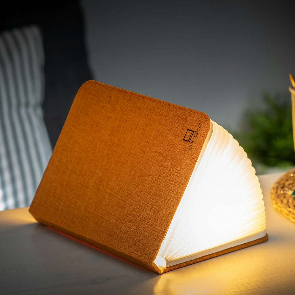 Gingko Design – Smart Book LED-lampe - Harmony Orange Hør - 2 Størrelser, sengelampe i form af en åben bog, der oplyser et mørkt rum