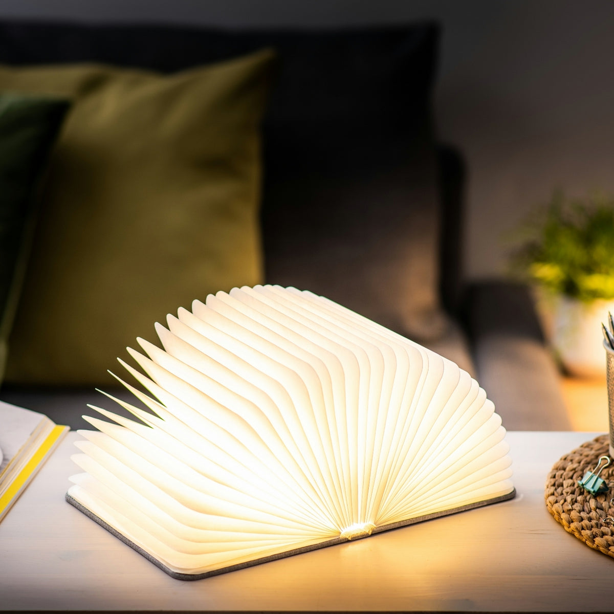 Gingko Design – Lámpara Smart Book LED - Lino Gris Urbano - 2 Tamaños, lámpara libro abierta y encendida en una mesita de noche, ambiente acogedor