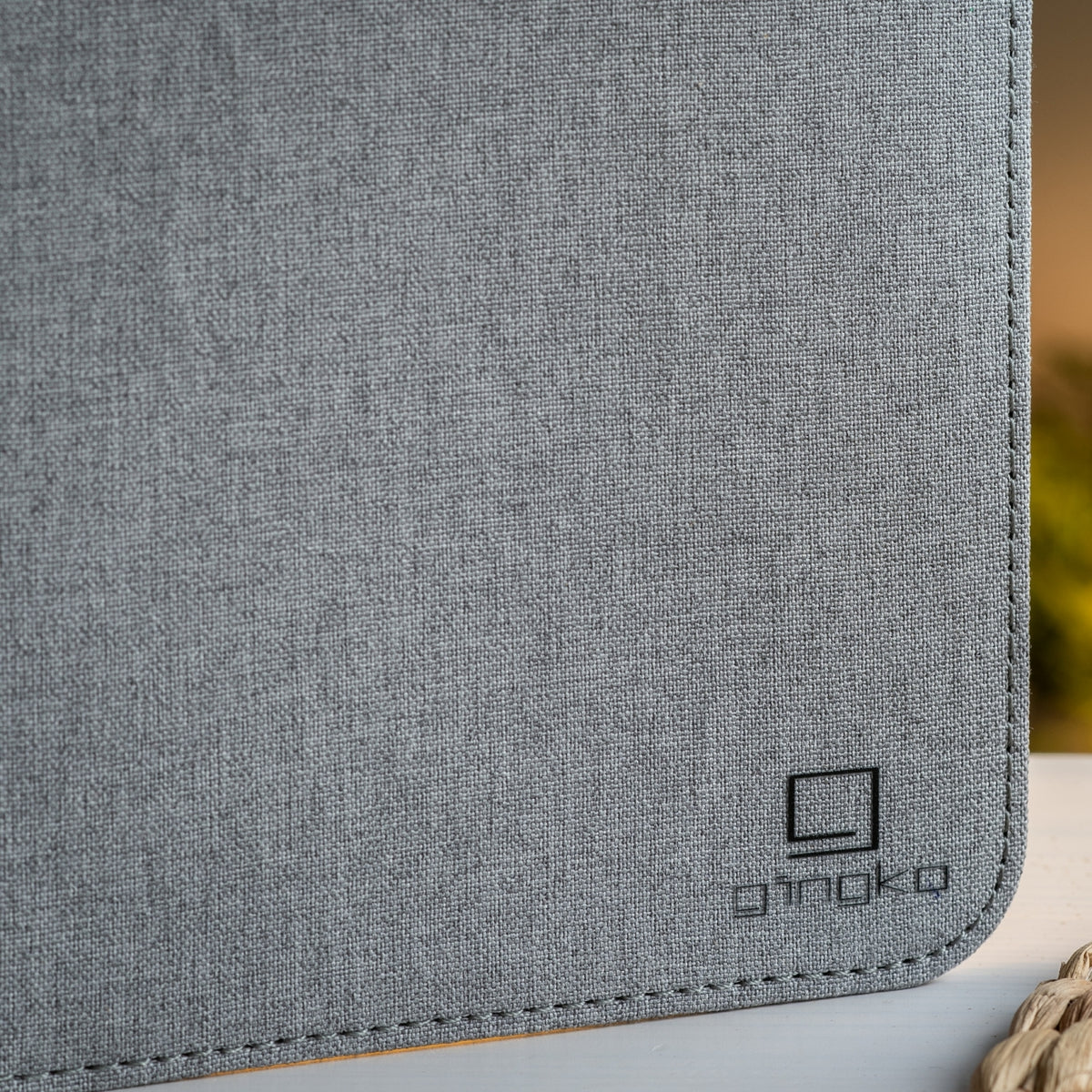 Gingko Design – Lámpara Smart Book LED - Lino Gris Urbano - 2 Tamaños, primer plano de tela gris con logotipo negro en la esquina inferior derecha