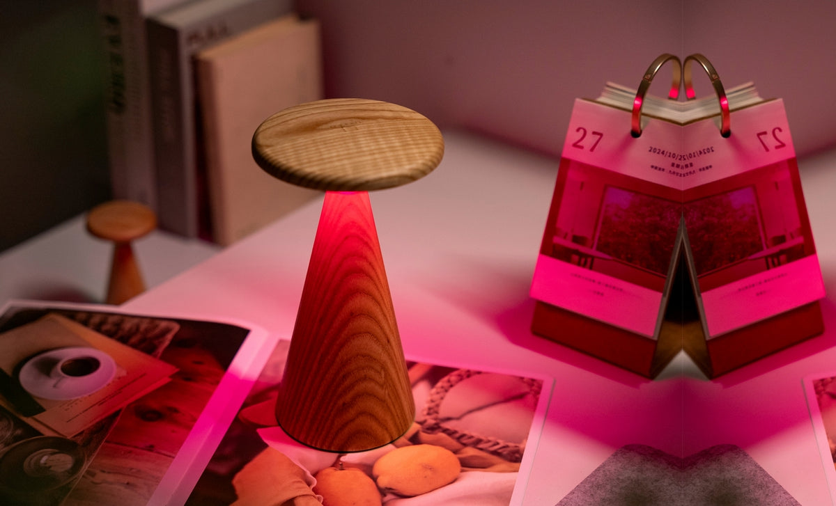 Gingko Design – Lámpara de mesa Sylva - Fresno blanco - 2 tamaños, una lámpara de mesa de madera con luz roja, junto a un calendario