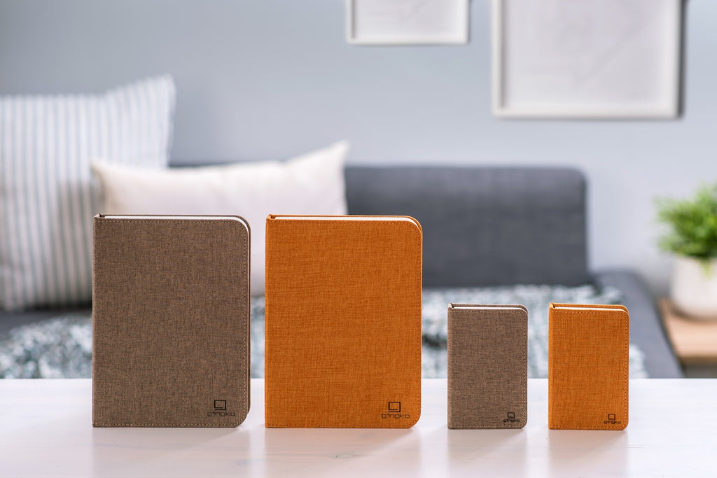Gingko Design – Smart Book LED-lampe - Harmony Orange Hør - 2 Størrelser, fire notesbøger i forskellige størrelser og farver på et bord