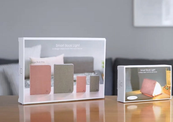 Gingko Design – Lámpara Smart Book LED - Lino Gris Urbano - 2 Tamaños, dos cajas de Smart Book Light sobre una mesa de madera