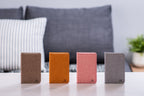 Gingko Design – Lampada Smart Book LED - Lino Marrone Caffè - Mini, quattro taccuini di colori diversi posati su un tavolino da salotto