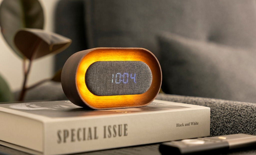 Gingko Design – Lumos Uhr - Oval Walnuss, digitaler Wecker aus Holz und Stoff auf einem Buch