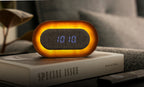 Gingko Design – Lumos Uhr - Oval Walnuss, ein leuchtender Wecker auf einem Buch in gemütlicher Atmosphäre