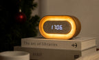 Gingko Design – Reloj Lumos - Ovalado Fresno Blanco, despertador digital de madera clara y tela gris, colocado sobre unos libros